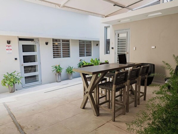 Un salón de conferencias con una mesa larga y seis sillas, plantas en macetas y una puerta con un letrero.