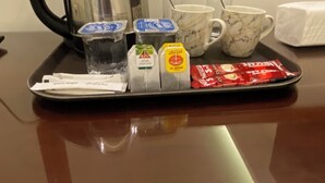 A tray with a kettle, cups, and tea packets on a reflective surface. - Eighth Wonders Hotel (Wadi Musa)