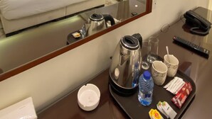 A hotel room with a bed, a large mirror, a television, a bathroom with a shower, and a tray with toiletries. - Eighth Wonders Hotel (Wadi Musa)