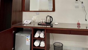 A hotel room with a wooden desk, a mirror, a television, a minibar, and a small refrigerator. - Eighth Wonders Hotel (Wadi Musa)