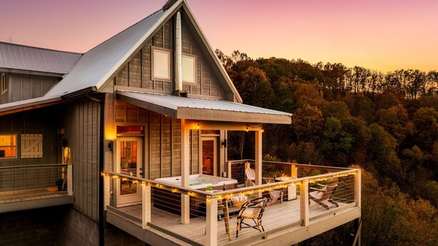 A wooden cabin with a balcony, a hot tub, and a deck chair. - Stunning View | Game Room Fun | Hot Tub & Fire Pit (Sevierville)