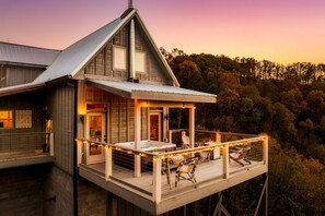 A wooden cabin with a balcony, a hot tub, and a deck chair. - Stunning View | Game Room Fun | Hot Tub & Fire Pit (Sevierville)