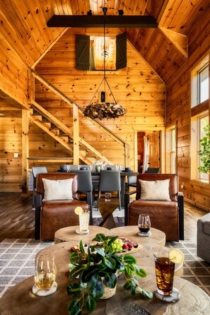 A wooden interior with a high ceiling, a staircase, and a dining area with a table and chairs. - Stunning View | Game Room Fun | Hot Tub & Fire Pit (Sevierville)