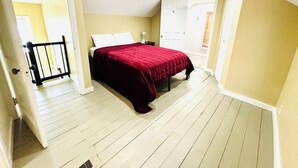 Un dormitorio con cama, mesita de noche, una puerta y una escalera.