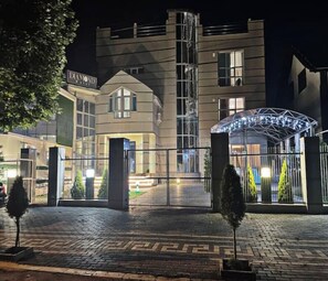 L’entrée d’un hôtel, avec une allée bordée de grilles, un espace d’entrée abrité et une façade de bâtiment moderne.