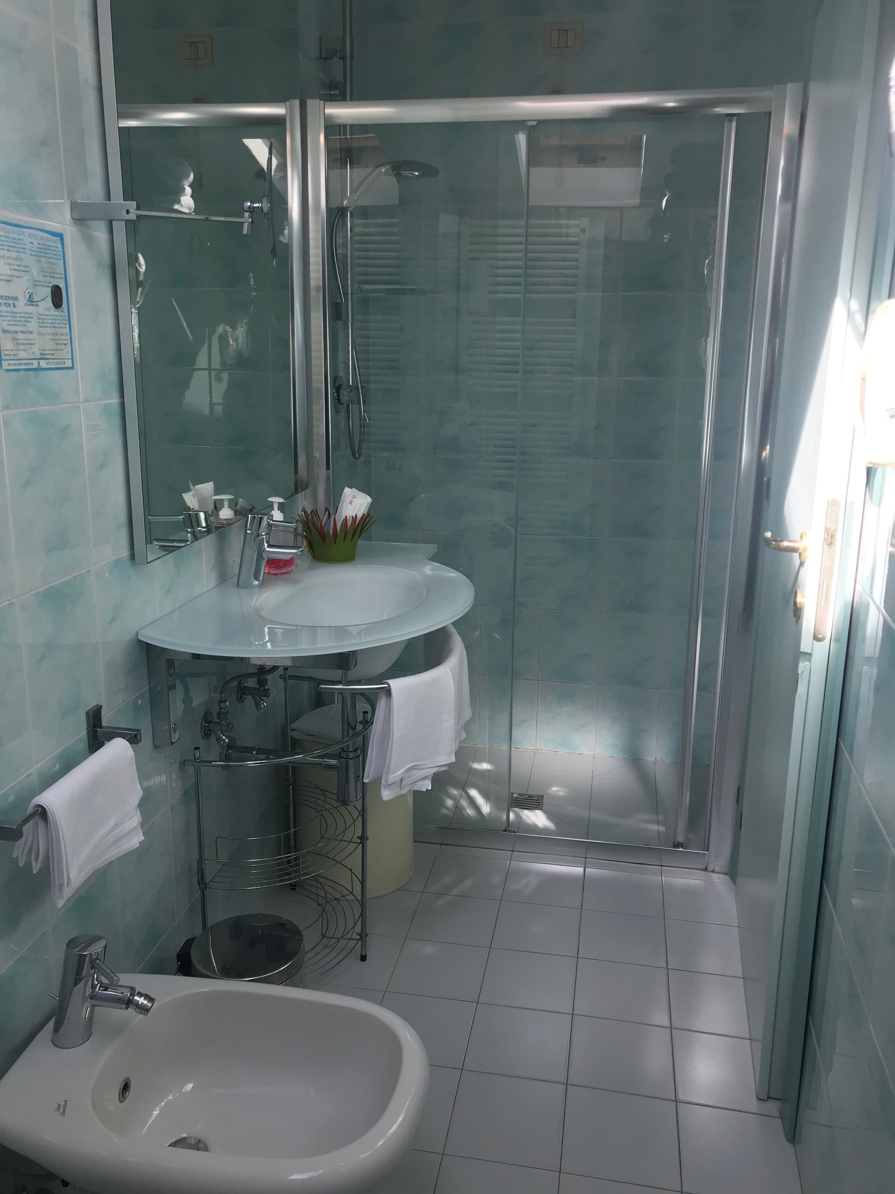 Ein modernes Badezimmer mit einer Glaskabine zur Dusche, einem Waschbecken mit Spiegel und einem Bidet.