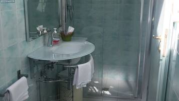 Ein modernes Badezimmer mit einer Glaskabine zur Dusche, einem Waschbecken mit Spiegel und einem Bidet.