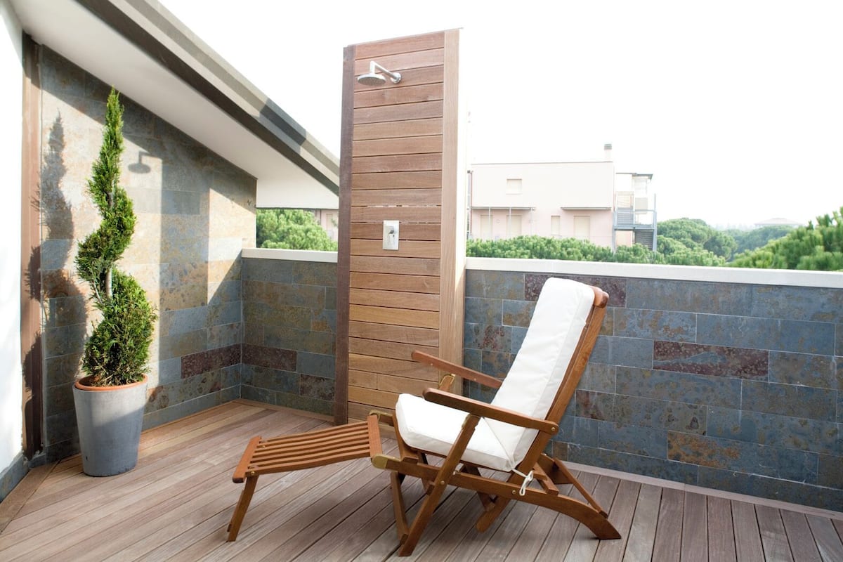A wooden deck with a wooden chair and a potted plant.