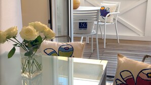 A room with a glass table, white chairs, and a vase with white roses. - Hotel Eros Residence (Cervia)