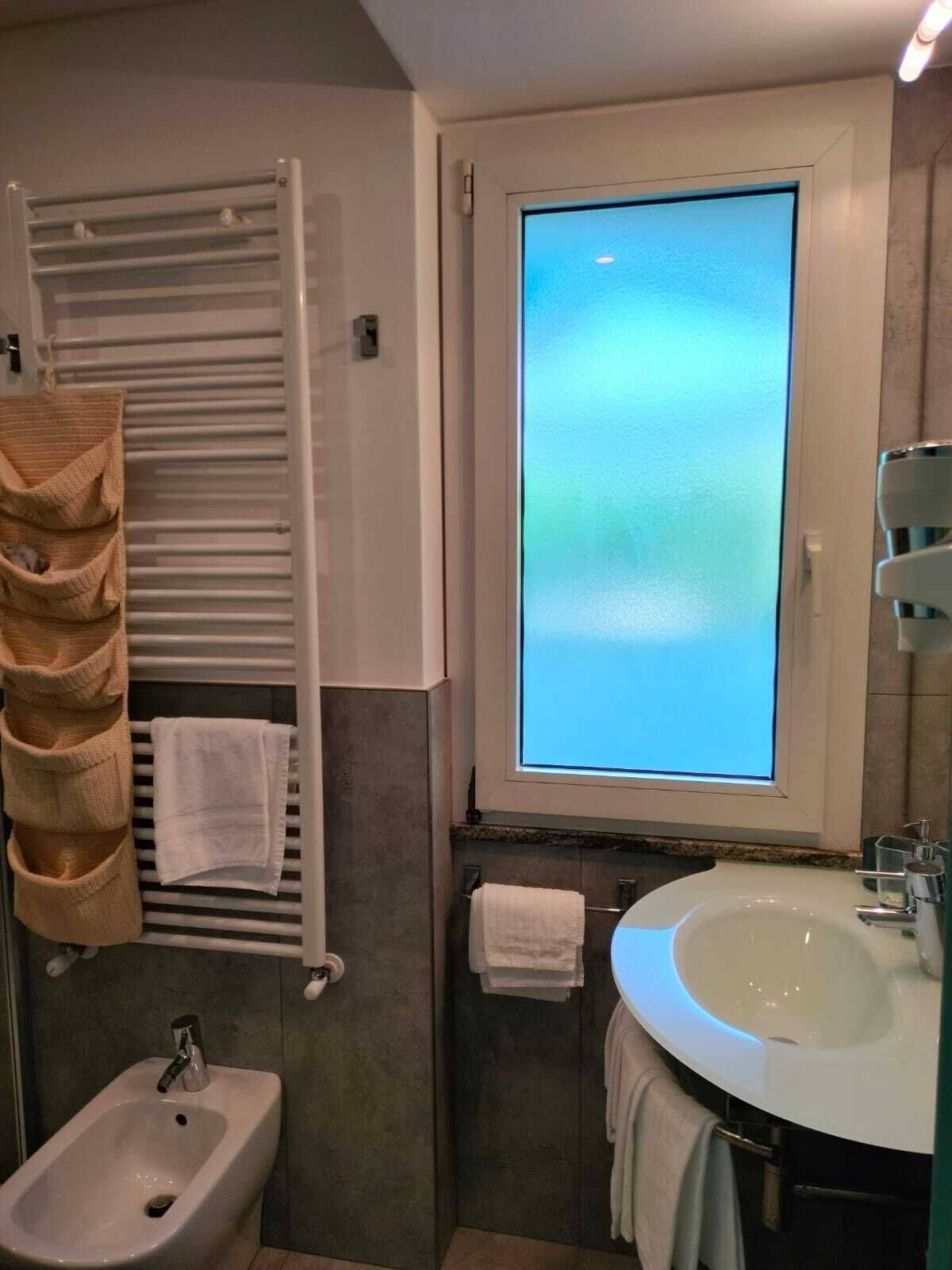 Un baño con bidé, lavamanos, toallero y ventana con vistas.