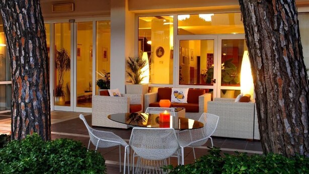 An outdoor seating area with wicker furniture, a glass table, and a candle. - Hotel Eros Residence (Cervia)