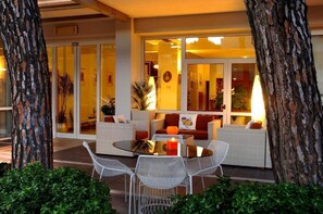 An outdoor seating area with wicker furniture, a glass table, and a candle. - Hotel Eros Residence (Cervia)