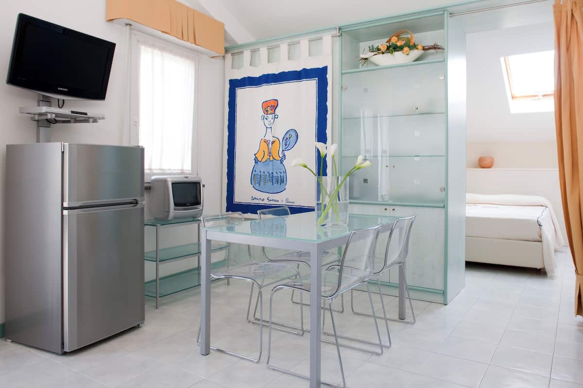 A modern kitchen with a refrigerator, microwave, and a glass dining table with chairs.