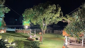 A well-lit outdoor area with a grassy lawn, trees, and a wooden structure. - Bonanza Piri Ranch (Pirenópolis)