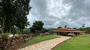 A stone pathway leading to a building with a red roof, surrounded by greenery and trees. - Bonanza Piri Ranch (Pirenópolis)