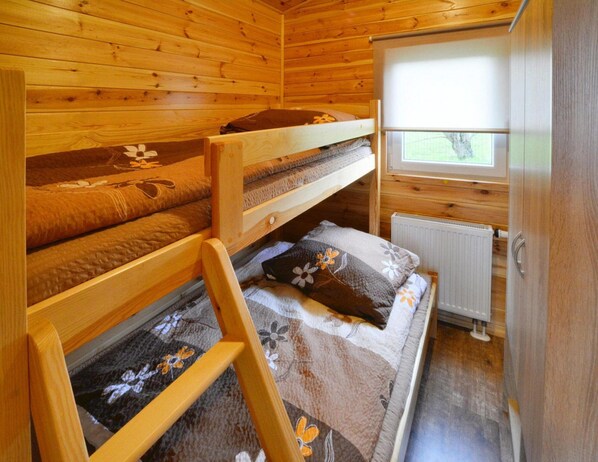 A wooden cabin with bunk beds, a window, and a radiator.