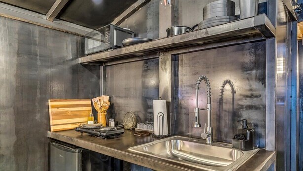 Une cuisine moderne équipée d’appareils électroménagers en acier inoxydable, d’une planche à découper en bois et d’un évier.