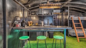 Une cuisine compacte avec un coin bar, des tabourets et une échelle.