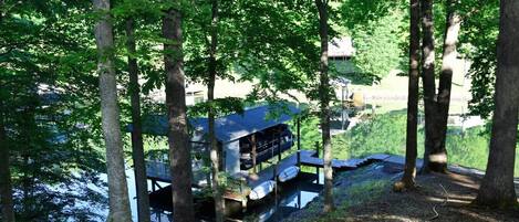 A cabin with a deck overlooking a body of water, surrounded by trees.