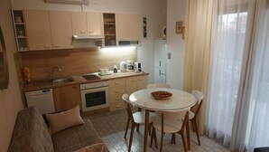 A compact kitchen with a dining area, a sofa, and a refrigerator. - Modern Trogir Apartment with Private Patio, BBQ, and Close to Beach - Two Bedroom Apartment (Trogir)