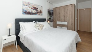 Une chambre à coucher moderne avec un grand lit, une armoire, une table de chevet et un tableau au mur.