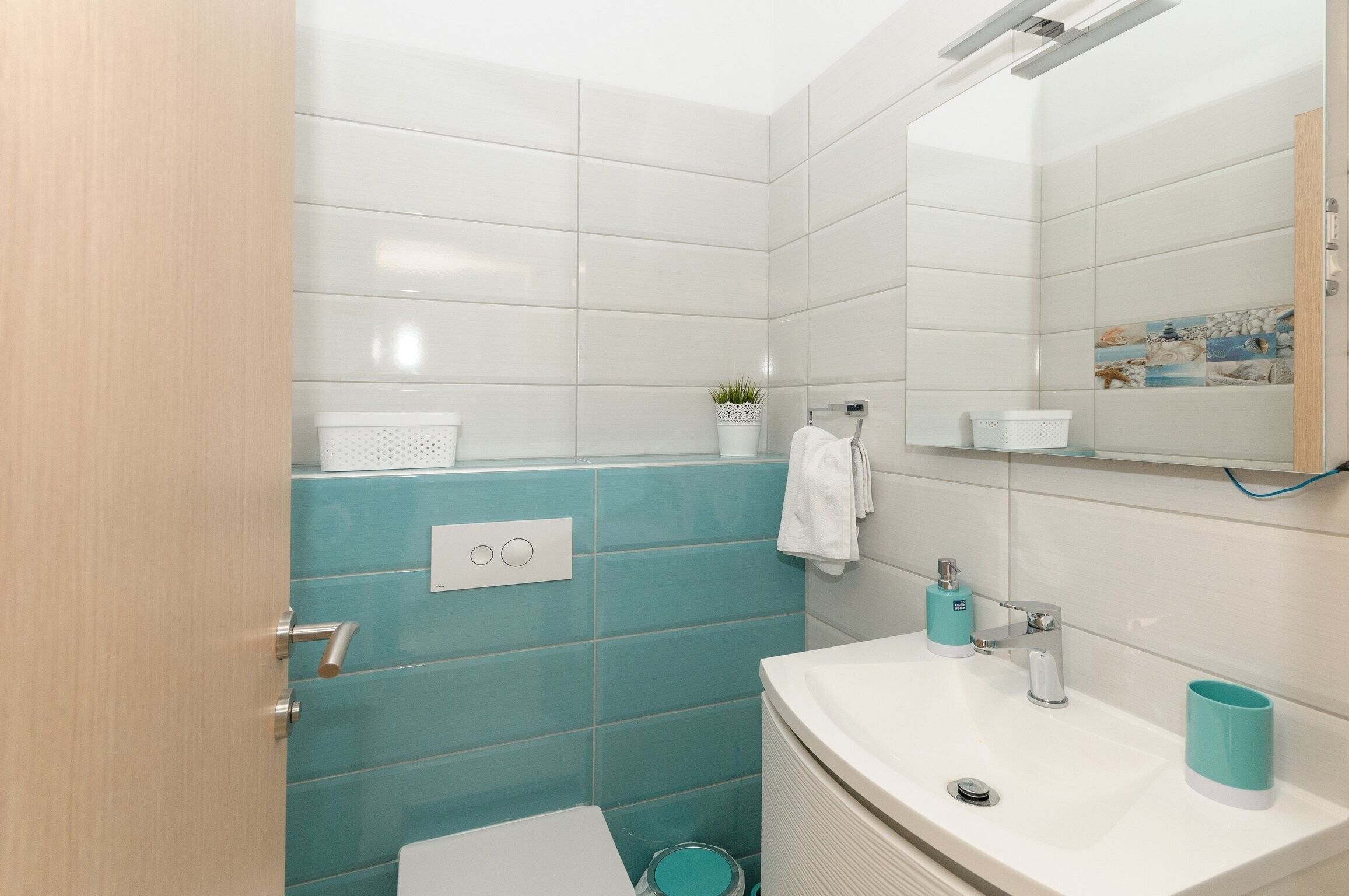 A modern bathroom with a white sink, a mirror, and a blue accent wall.