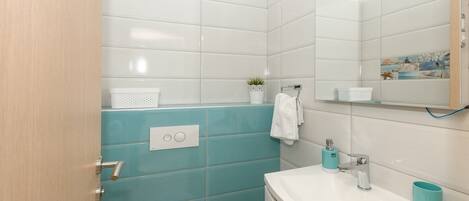 A modern bathroom with a white sink, a mirror, and a blue accent wall.