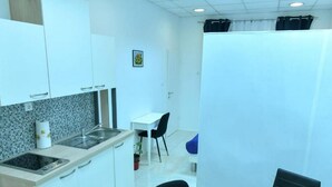 Een compacte keuken met witte kastjes, een spoelbak en een klein eethoekje met een tafel en stoelen.