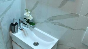 Een badkamer met een witte wastafel, een spiegel en een toilet.