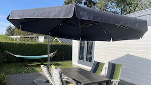 Un patio al aire libre con mesa y sillas, una hamaca y un paraguas grande.