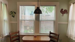 A dining area with a wooden table and chairs, a hanging pendant light, and a window with blinds. - Tranquil bungalow with WiFi in charming Bridgton (Bridgton)