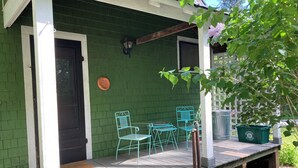 A porch with a green wall, two metal chairs, a table, and a trash bin. - Tranquil bungalow with WiFi in charming Bridgton (Bridgton)