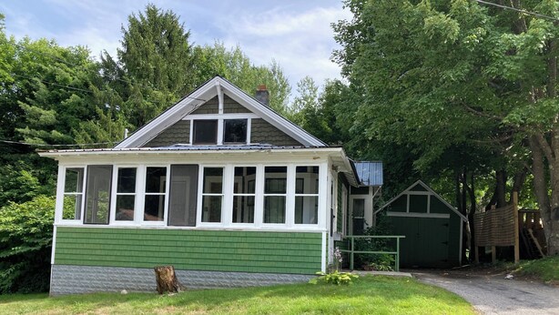 A small, single-story house with a green and white exterior, a front porch, and a garage. - Tranquil bungalow with WiFi in charming Bridgton (Bridgton)
