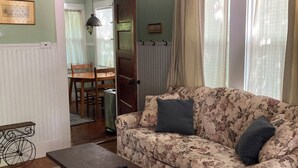 A living room with a floral sofa, a coffee table, and a dining area visible through an open door. - Tranquil bungalow with WiFi in charming Bridgton (Bridgton)