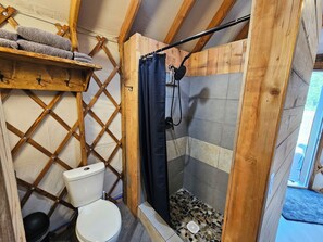 Un intérieur en bois comprenant des toilettes, une douche et une étagère avec des serviettes.
