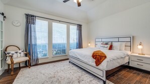 A bedroom with a bed, nightstands, a chair, a ceiling fan, and a view through the windows. - Modern & Spacious 3BD/2BA Luxury in Central Frisco (Frisco)