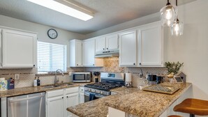 A modern kitchen with white cabinets, granite countertops, stainless steel appliances, and a clock on the wall. - Modern & Spacious 3BD/2BA Luxury in Central Frisco (Frisco)