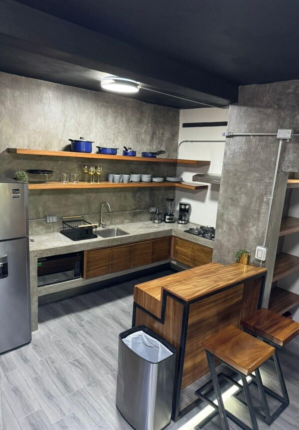Une cuisine moderne dotée d’un îlot central, de meubles en bois et d’un évier en acier inoxydable.