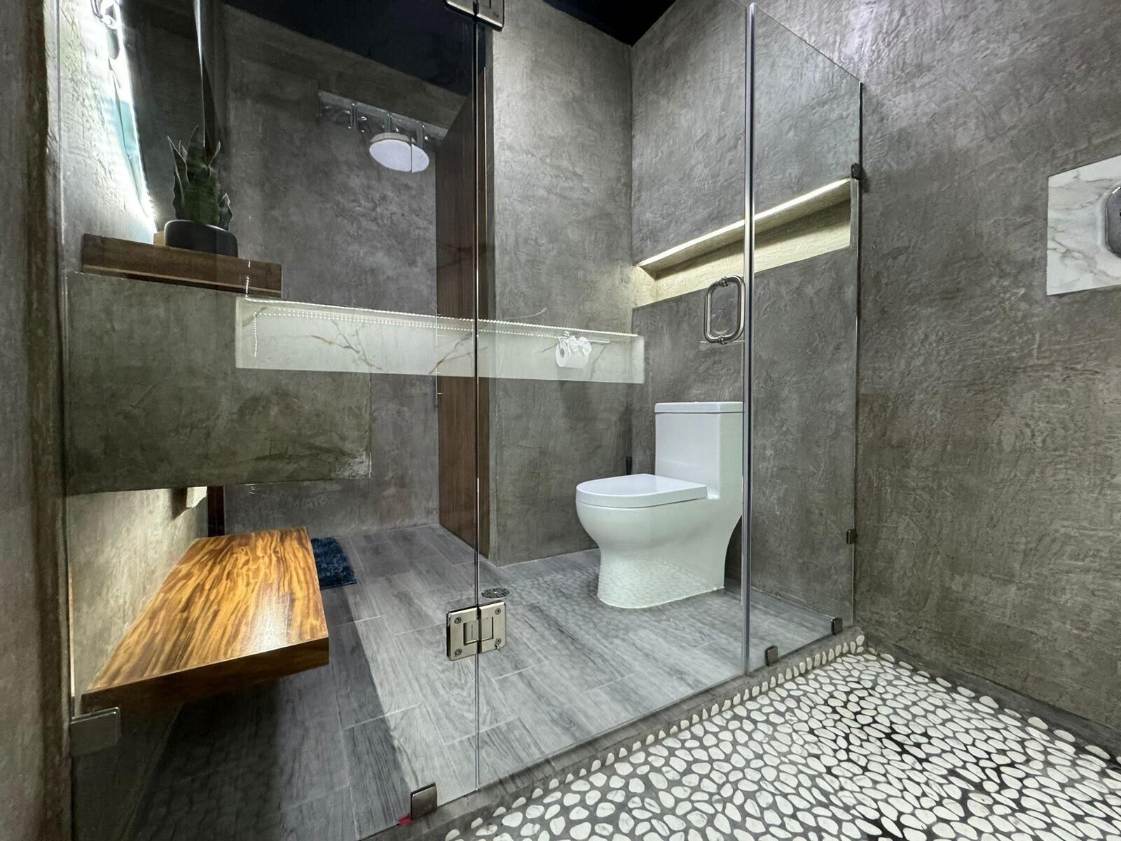 Un baño moderno con cabina de ducha de vidrio, inodoro y tocador de madera.