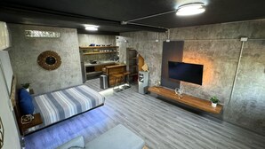 A compact studio apartment with a bed, kitchenette, and a TV mounted on the wall. - Cozy chic studio near the beach! (Puerto Vallarta)