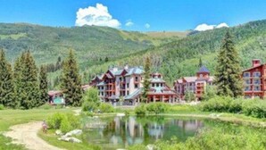 A lodge with multiple buildings, a pond, and surrounding forested hills. - New! Eagle Springs Chalet (Brighton)