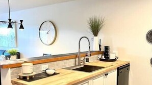 A modern kitchen with a wooden countertop, white cabinets, a sink, and a dishwasher. - New! Eagle Springs Chalet (Brighton)