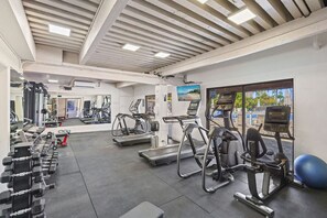 Une salle de sport équipée de tapis de course, de vélos elliptiques et de poids libres.