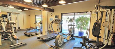 Bright on-site gym with cardio machines, weights, and natural light