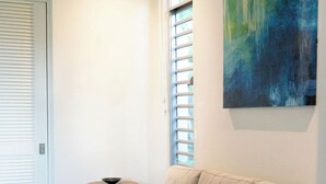Una sala de estar moderna con un sofá beige, una mesa de centro de madera y un cuadro en la pared.