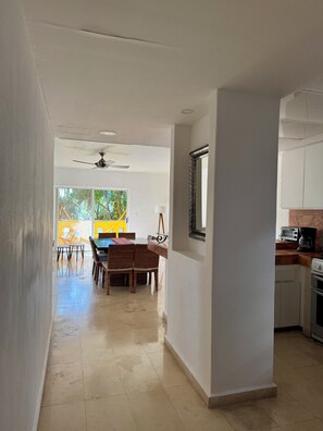 A modern kitchen with white cabinets, a dining area with wicker chairs, and a ceiling fan.