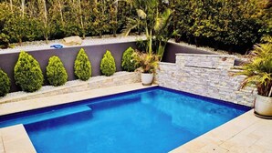 Ein rechteckiger Pool mit Steinrand und gefliestem Deck.