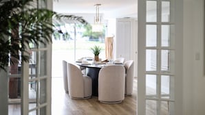 A dining area with a round table, four chairs, and a hanging light fixture. - 702A | Waterfront | Sleeps 8 | Heated Pool |Tiki Hut |Fire Pit |by DelrayNightly (Delray Beach)
