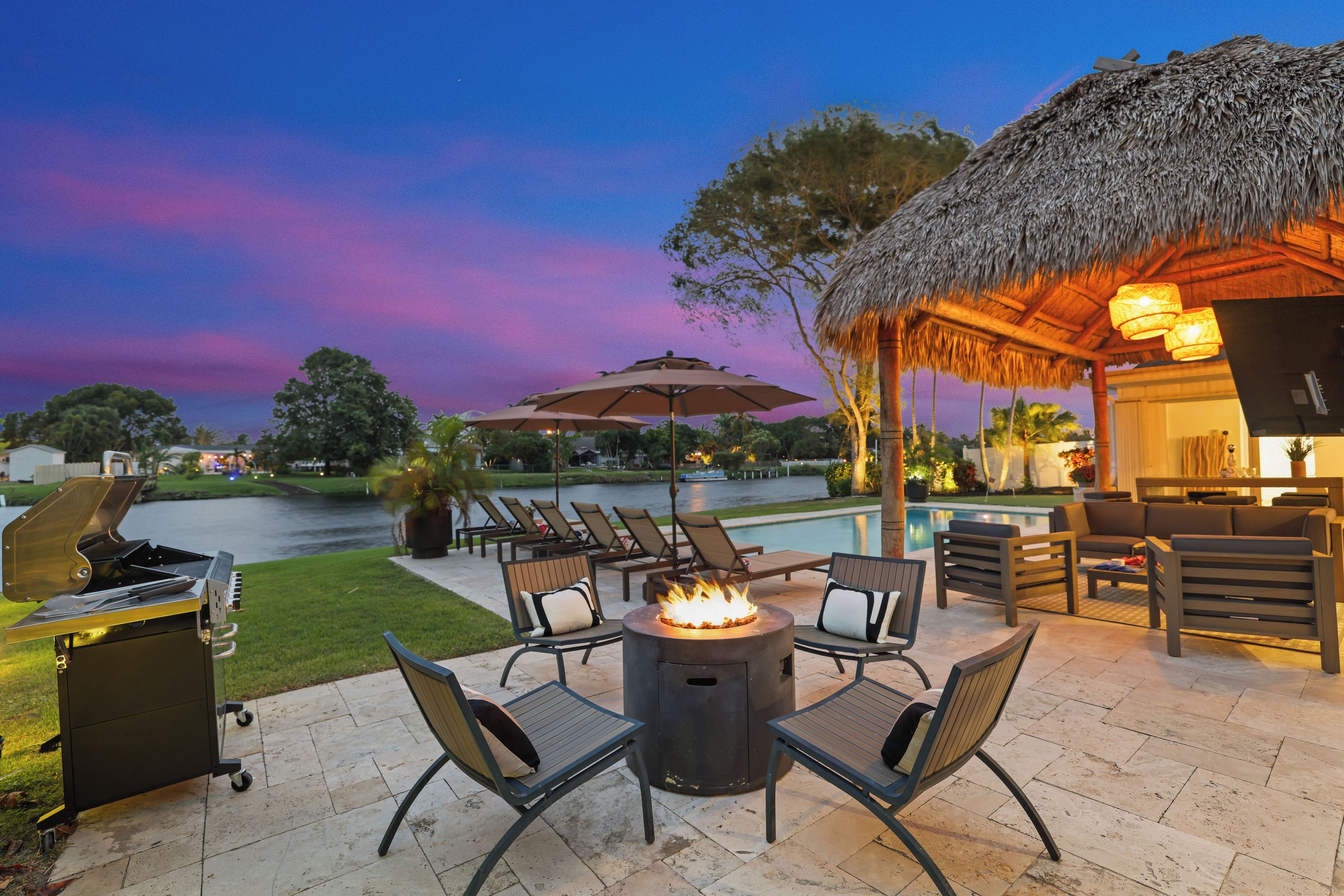 An outdoor patio with a fire pit, lounge chairs, and a pool area.
