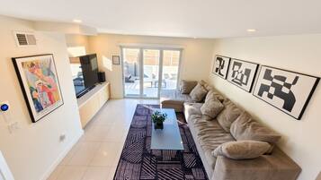 Een moderne woonkamer met een bank, een salontafel en kunstwerken aan de wanden.